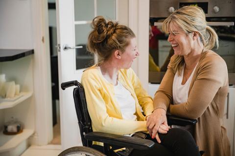 jeune femme handicapée en fauteil sourit à sa maman.