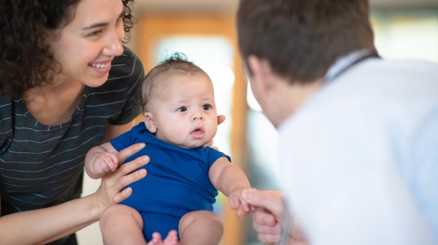 Un médecin ausculte un bébé, tenu par sa maman