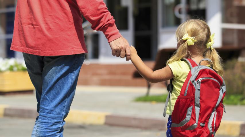 Adulte tenant un enfant par la main pour l'accompagner à l'école